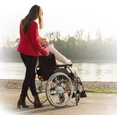 Young woman taking care of her grandma who is sitting in a wheelchair